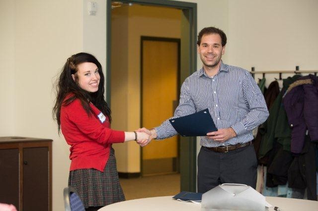 Presenter shaking hands with woman during certificate presentation both are smiling